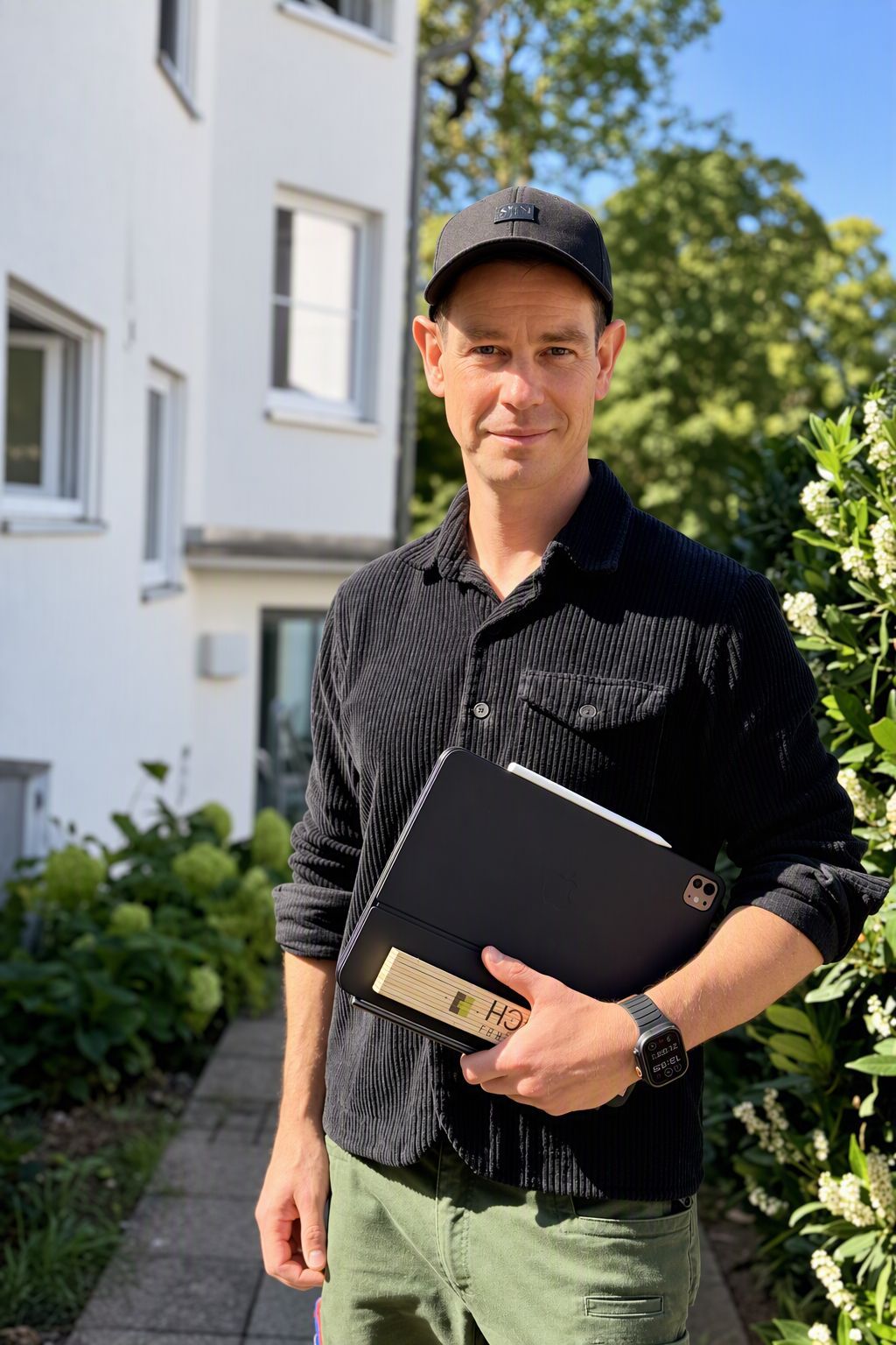 Porträt Jochen Decker mit Mappe im Grünen